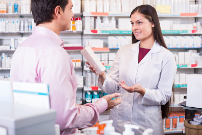 helpful pharmacist serving and consulting man at a pharmacy 